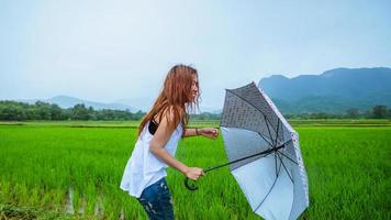 Asian women travel relax in the holiday.The girl smiled happy and enjoyed the rain that was falling. travelling in countrysde, Green rice fields, Travel Thailand. photo