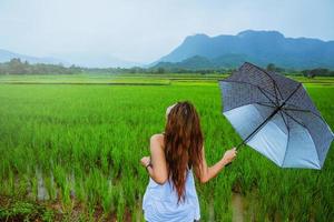 Asian women travel relax in the holiday.The girl smiled happy and enjoyed the rain that was falling. travelling in countrysde, Green rice fields, Travel Thailand. photo