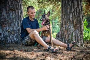 el joven hipster caucásico pasa tiempo con su perro en el parque en un día soleado de verano. el concepto de una mascota como miembro de la familia foto