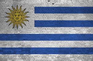 Uruguay flag depicted in paint colors on old brick wall. Textured banner on big brick wall masonry background photo