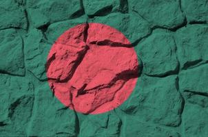 bandera de bangladesh representada en colores de pintura en el primer plano de la pared de piedra antigua. banner texturizado sobre fondo de pared de roca foto