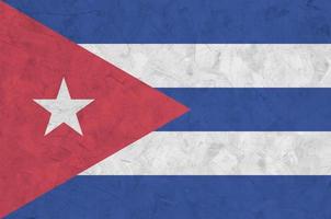 Cuba flag depicted in bright paint colors on old relief plastering wall. Textured banner on rough background photo