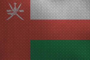 Oman flag depicted in paint colors on old brushed metal plate or wall closeup. Textured banner on rough background photo