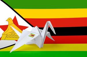 Zimbabwe flag depicted on paper origami crane wing. Handmade arts concept photo