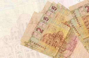 2 billetes de hryvnias ucranianos se encuentran apilados en el fondo de un gran billete semitransparente. presentación abstracta de la moneda nacional foto