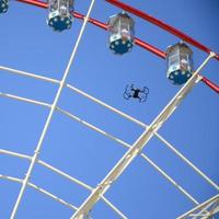 Drone take off from land and flying for take photo front of ferris wheel