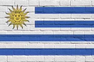 Uruguay flag depicted in paint colors on old brick wall. Textured banner on big brick wall masonry background photo