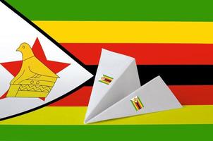Zimbabwe flag depicted on paper origami airplane. Handmade arts concept photo
