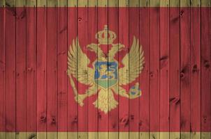 bandera de montenegro representada en colores de pintura brillante en la pared de madera vieja. banner texturizado sobre fondo áspero foto