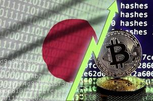 bandera de japón y flecha verde ascendente en la pantalla de minería bitcoin y dos bitcoins dorados físicos foto