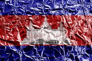Cambodia flag depicted in paint colors on shiny crumpled aluminium foil closeup. Textured banner on rough background photo