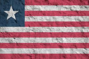 Liberia flag depicted in bright paint colors on old relief plastering wall. Textured banner on rough background photo