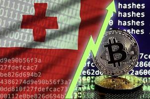 bandera de tonga y flecha verde ascendente en la pantalla de minería bitcoin y dos bitcoins dorados físicos foto