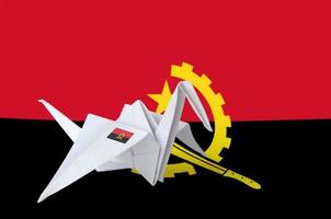 Angola flag depicted on paper origami crane wing. Handmade arts concept