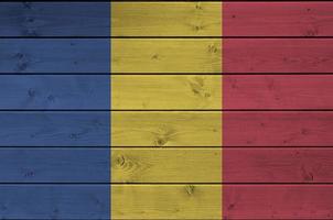Romania flag depicted in bright paint colors on old wooden wall. Textured banner on rough background photo