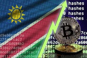 bandera de namibia y flecha verde ascendente en la pantalla de minería bitcoin y dos bitcoins dorados físicos foto