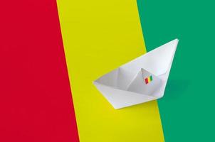 Guinea flag depicted on paper origami ship closeup. Handmade arts concept photo