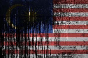 Malaysia flag depicted in paint colors on old and dirty oil barrel wall closeup. Textured banner on rough background photo