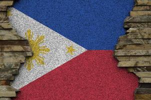 Philippines flag depicted in paint colors on old stone wall closeup. Textured banner on rock wall background photo