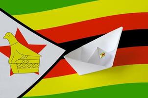 Zimbabwe flag depicted on paper origami ship closeup. Handmade arts concept photo