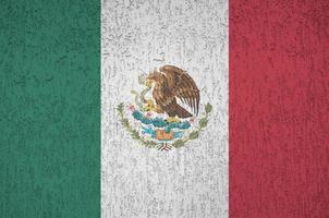 Mexico flag depicted in bright paint colors on old relief plastering wall. Textured banner on rough background photo