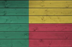 Benin flag depicted in bright paint colors on old wooden wall. Textured banner on rough background photo