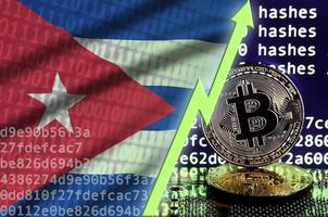 bandera de cuba y flecha verde ascendente en la pantalla de minería bitcoin y dos bitcoins dorados físicos foto