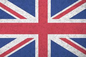 Great britain flag depicted in bright paint colors on old relief plastering wall. Textured banner on rough background photo