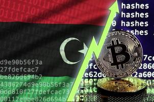 bandera de libia y flecha verde ascendente en la pantalla de minería bitcoin y dos bitcoins dorados físicos foto