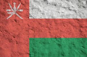 Oman flag depicted in bright paint colors on old relief plastering wall. Textured banner on rough background photo