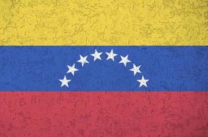 Venezuela flag depicted in bright paint colors on old relief plastering wall. Textured banner on rough background photo