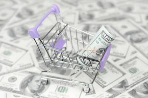 Small shopping trolley with dollars banknotes. Concept of cashback and bargains on sale photo