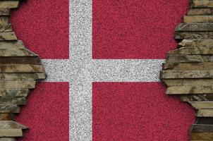 Denmark flag depicted in paint colors on old stone wall closeup. Textured banner on rock wall background photo