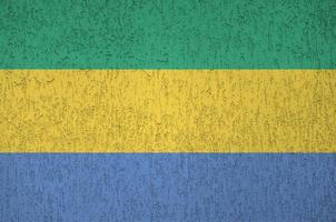 Gabon flag depicted in bright paint colors on old relief plastering wall. Textured banner on rough background photo