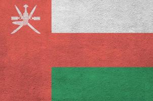 Oman flag depicted in bright paint colors on old relief plastering wall. Textured banner on rough background photo