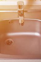 Empty clean silvery kitchen sink and water faucet close up photo