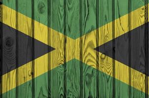 Jamaica flag depicted in bright paint colors on old wooden wall. Textured banner on rough background photo