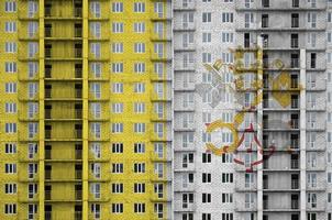 Vatican City State flag depicted in paint colors on multi-storey residental building under construction. Textured banner on brick wall background photo