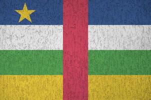 Central African Republic flag depicted in bright paint colors on old relief plastering wall. Textured banner on rough background photo