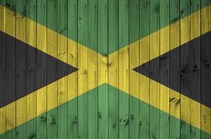 Jamaica flag depicted in bright paint colors on old wooden wall. Textured banner on rough background photo