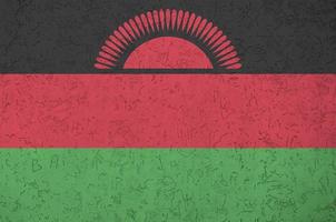 Malawi flag depicted in bright paint colors on old relief plastering wall. Textured banner on rough background photo