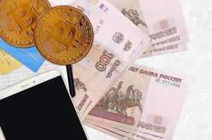 100 russian rubles bills and golden bitcoins with smartphone and credit cards. Cryptocurrency investment concept. Crypto mining or trading photo