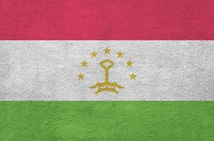 bandera de tayikistán representada en colores de pintura brillante en la antigua pared de yeso en relieve. banner texturizado sobre fondo áspero foto