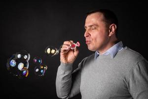 handsome man in a suit is blowing soap bubbles. photo