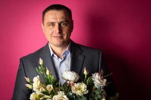 handsome businessman in a suit looks at the camera with a bouquet of flowers. photo