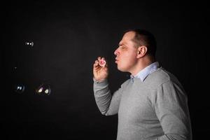 handsome man in a suit is blowing soap bubbles. photo