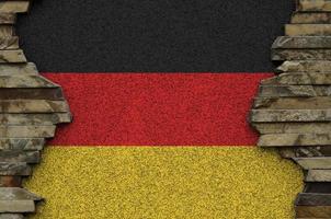 Germany flag depicted in paint colors on old stone wall closeup. Textured banner on rock wall background photo