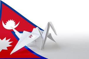 Nepal flag depicted on paper origami crane wing. Handmade arts concept photo