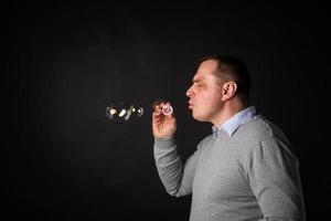 handsome man in a suit is blowing soap bubbles. photo