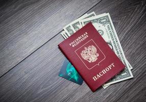un pasaporte extranjero y dólares sobre un fondo de madera. foto